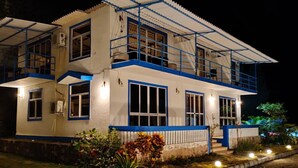 A two-story house with a balcony, a covered porch, and a well-lit exterior. - Sea Breeze Beach Resort (Murud)