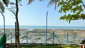 A beach view with a chain-link fence, a hammock, and a lamp post. - Sea Breeze Beach Resort (Murud)