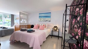 A bedroom with a bed, a nightstand, a window, and a wall with a floral pattern.