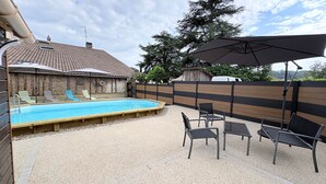 A backyard with a swimming pool, outdoor furniture, and a wooden fence.