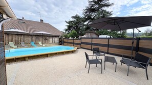 A backyard with a swimming pool, outdoor furniture, and a wooden fence.