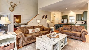 Ein großzügiger Wohnraum mit Ledersofas, einem Couchtisch und einem aufgehängten Hirschkopf.