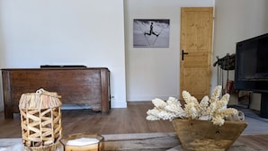 A cozy living room with a wooden sofa, a small table with a candle, a decorative basket, and a framed picture on the wall. - COMFORTABLE CHALET - QUIET AND CLOSE TO EVERYTHING (Colmars)