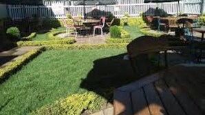 A patio area with outdoor seating and a white picket fence in the background.