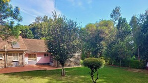 A house with a stone facade and a tiled roof, surrounded by a well-maintained lawn and trees.