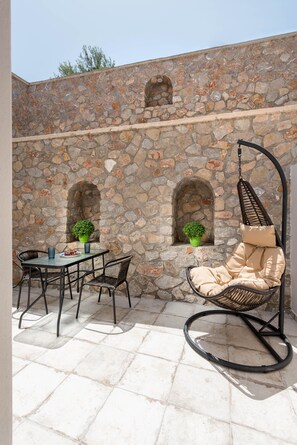 A stone wall with a hanging chair and a table with chairs.