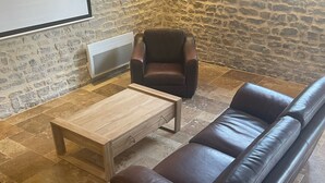 Ein Wohnzimmer mit braunem Ledersofa, einem Holztisch und einer Steinwand.