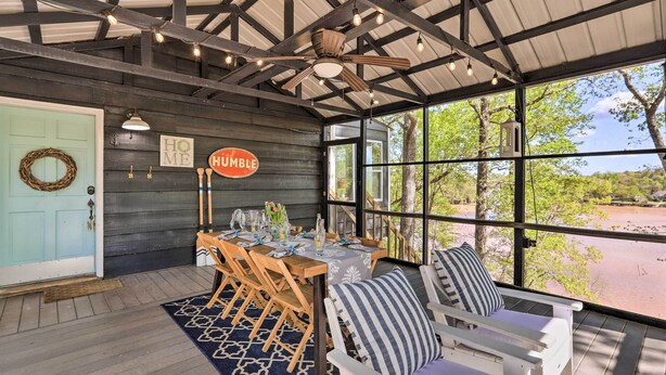 A covered outdoor dining area with a table set for four, wooden chairs, a ceiling fan, and a view of a natural landscape. - 'The Chalet on Sinclair' w/ Private Dock & Kayaks! (Eatonton)