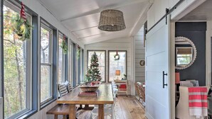 A cozy room with a wooden dining table, white walls, and large windows. - 'The Chalet on Sinclair' w/ Private Dock & Kayaks! (Eatonton)