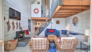 A cozy interior with a fireplace, wicker furniture, a staircase, and a living area with sofas and a coffee table. - 'The Chalet on Sinclair' w/ Private Dock & Kayaks! (Eatonton)