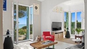 Un salon moderne avec un téléviseur, un fauteuil rouge et une table basse en bois.