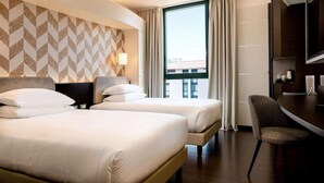 A hotel room with two beds, a desk, a chair, and a large window with curtains. - Doubletree BY Hilton Milan Malpensa (SOLBIATE OLONA)