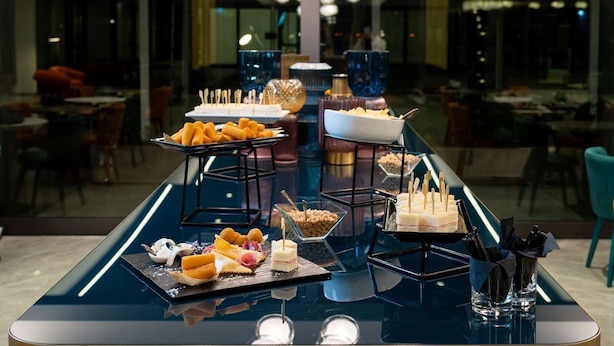 A buffet setup with various food items and utensils on a reflective table. - Doubletree BY Hilton Milan Malpensa (SOLBIATE OLONA)