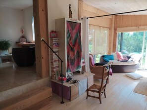 A modern interior with a staircase, a bookshelf, a wicker chair, and a sofa with a laptop.
