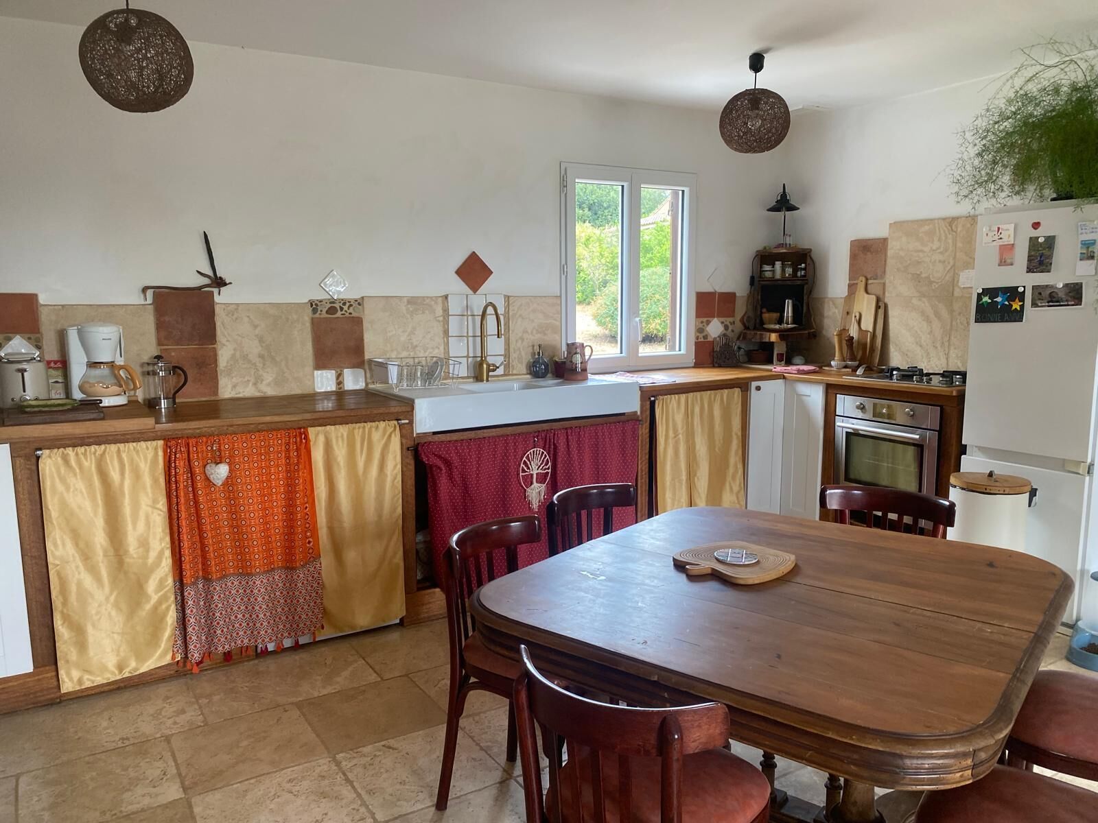 A kitchen with a dining table, chairs, a window, and a refrigerator.