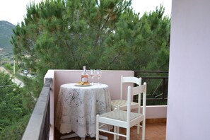 A balcony with a white table and chair, a bottle, and two glasses. - CAROLINAS'APARTMENT CARDEDU (Cardedu)