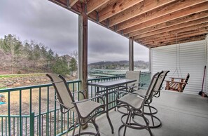 A covered outdoor seating area with a table and chairs, overlooking a landscaped area with trees and a distant view of houses. - Lake-View Patio, Pool Table! Camdenton Family Unit (Camdenton)