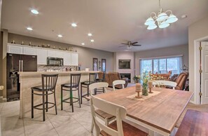 A modern kitchen with a central island, a dining area with a wooden table and chairs, and a ceiling fan.