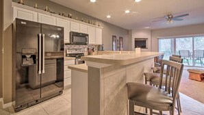 Una cocina moderna con una isla grande, muebles blancos, electrodomésticos de acero inoxidable y un comedor con sillas.