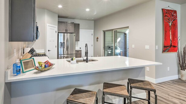 A modern kitchen with a large island, stainless steel appliances, and two bar stools. - Modern Flagstaff Home, 4 Mi to Downtown! (Flagstaff)