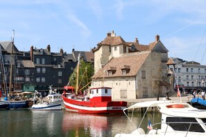 A harbor with boats docked, a historic building with a stone facade, and a clear sky.