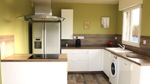 A compact kitchen with a built-in washing machine, a coffee maker, and a window providing natural light.