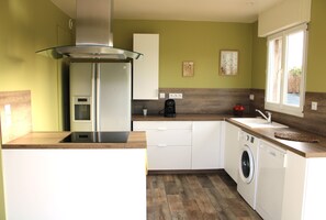 A compact kitchen with a built-in washing machine, a coffee maker, and a window providing natural light.