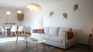 A modern living room with a sofa, a dining table with chairs, and a coffee table.