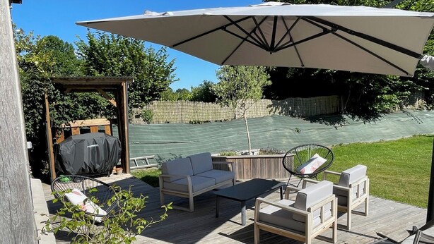 A wooden deck with outdoor furniture, including a sofa, chairs, and a table.