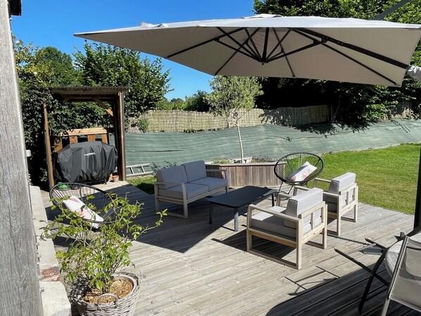 Um deck de madeira com mobiliário externo, incluindo um sofá, cadeiras e uma mesa.