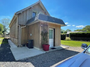 A two-story wooden house with a sloped roof, a front door, and a small porch area.