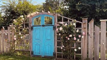 Une porte en bois peinte en bleu, encadrée par une clôture en bois et ornée de rosiers grimpants.