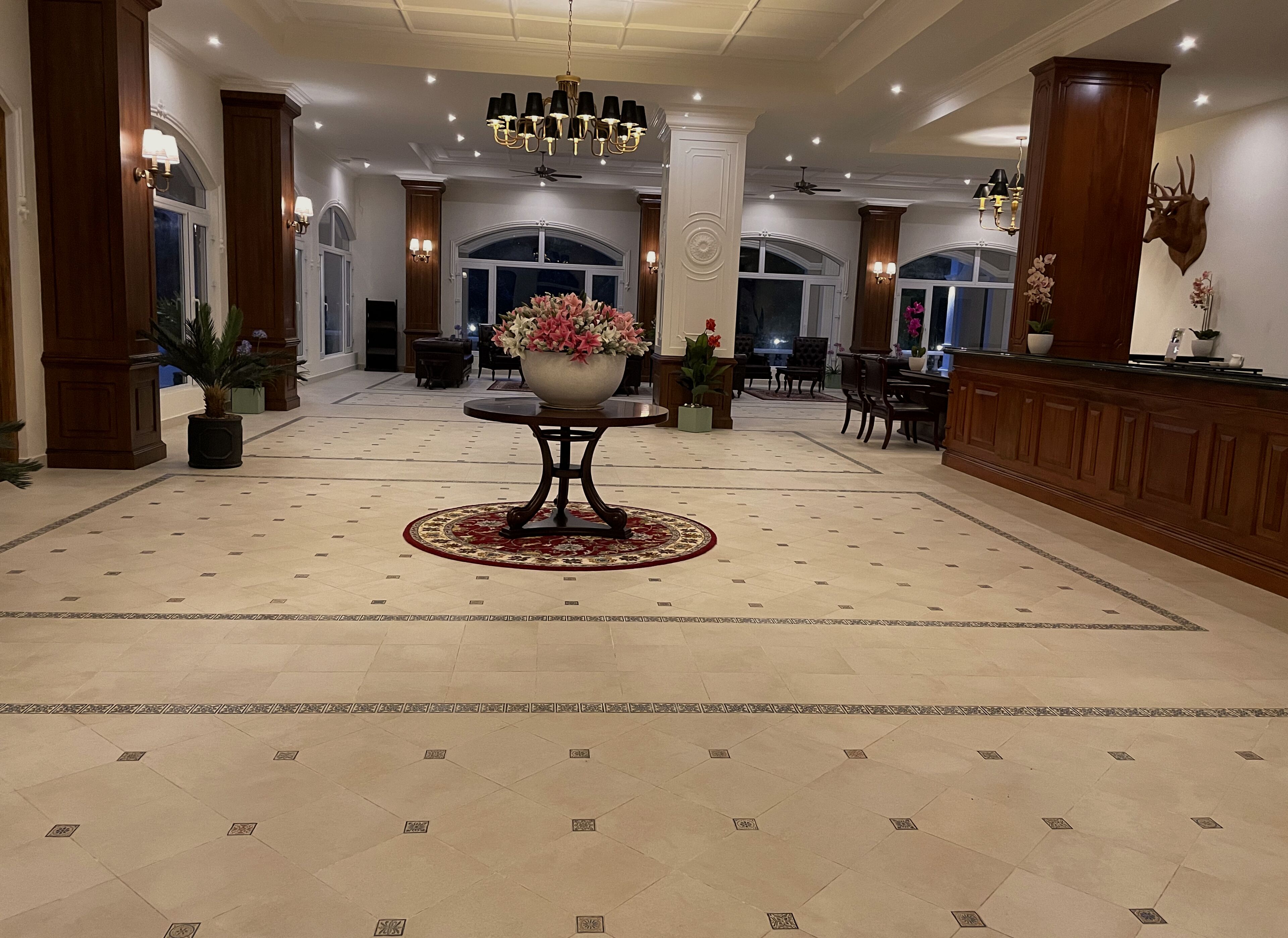 Un vestíbulo espacioso con una mesa redonda central, elegantes candelabros y un gran arreglo floral.