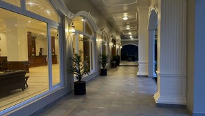 A corridor with large windows, potted plants, and a reception desk. - Montrose Golf Resort & Spa (Somvarpet)