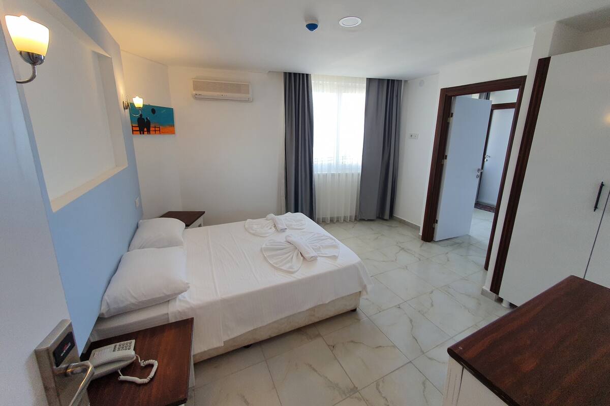 A hotel room with a bed, bedside tables, a phone, and a painting on the wall.