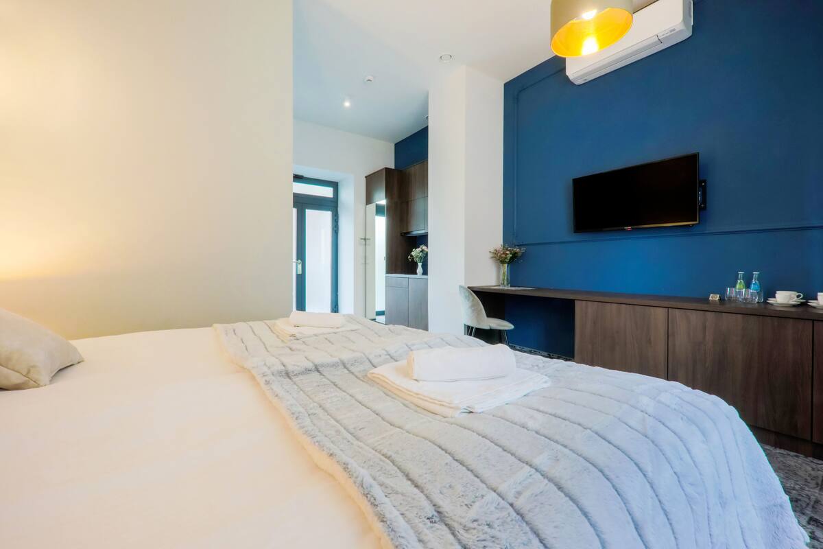 Een hotelkamer met een groot bed, een flatscreen televisie aan de muur, een houten dressoir en een bureau met een stoel.