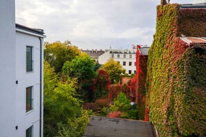 Un edificio con fachada blanca y tejado rojo, rodeado de abundante vegetación y árboles con hojas otoñales.