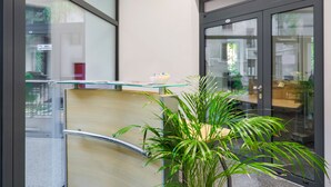Un intérieur moderne avec une cloison en verre, un bureau en bois et une plante en pot.