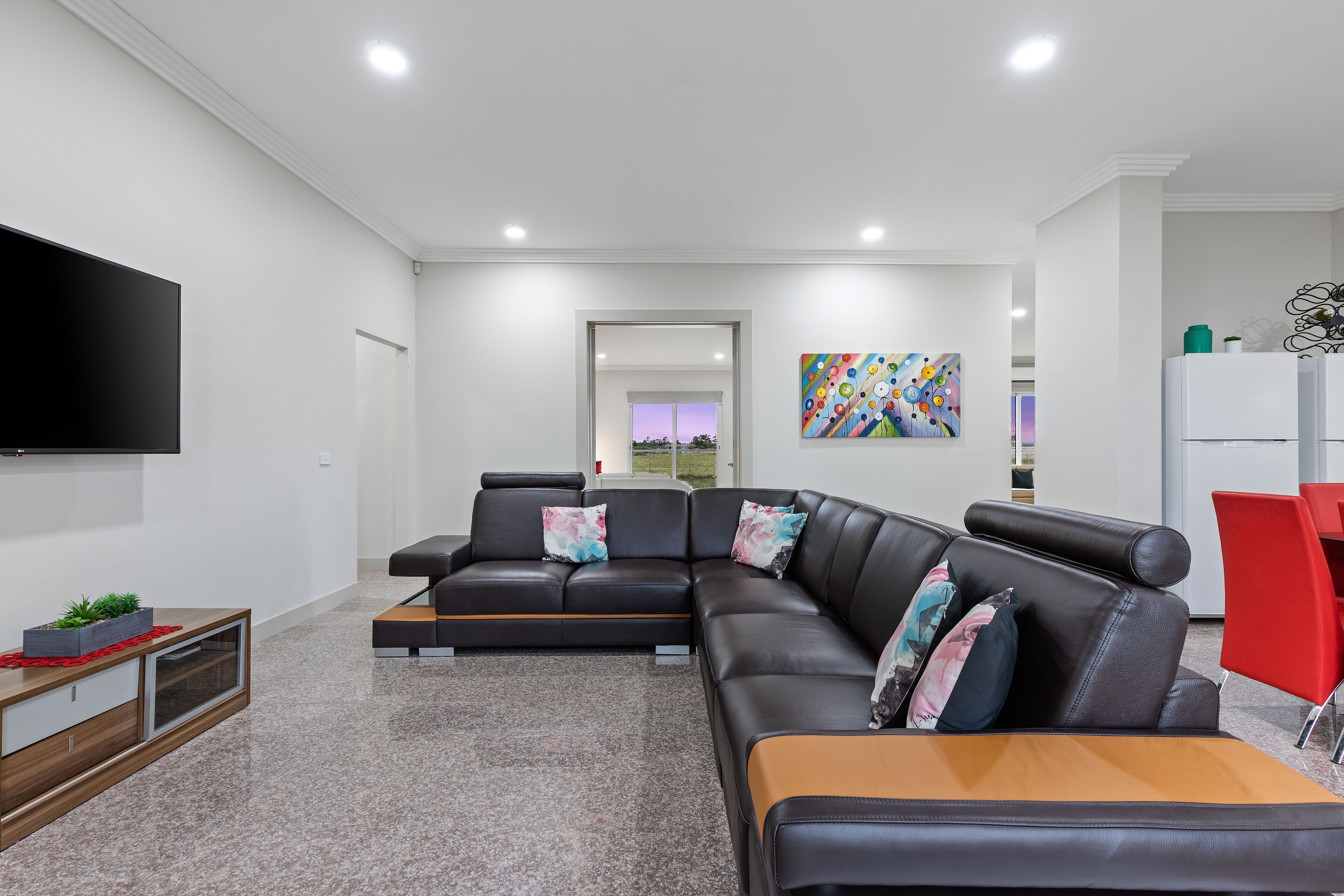 A modern living room with a sectional sofa, a flat-screen TV, and a red chair.