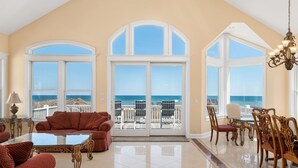 A spacious living room with a large glass door leading to a balcony overlooking the ocean. - Imperial Palace Pool + Oceanfront + Pets Stay Free (Kill Devil Hills)