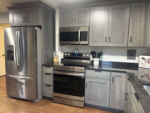 A kitchen with stainless steel appliances, wooden cabinets, and a microwave.