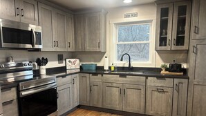 A kitchen with grey cabinets, stainless steel appliances, a window with a view, and a sign reading 'FARM FRESH'.