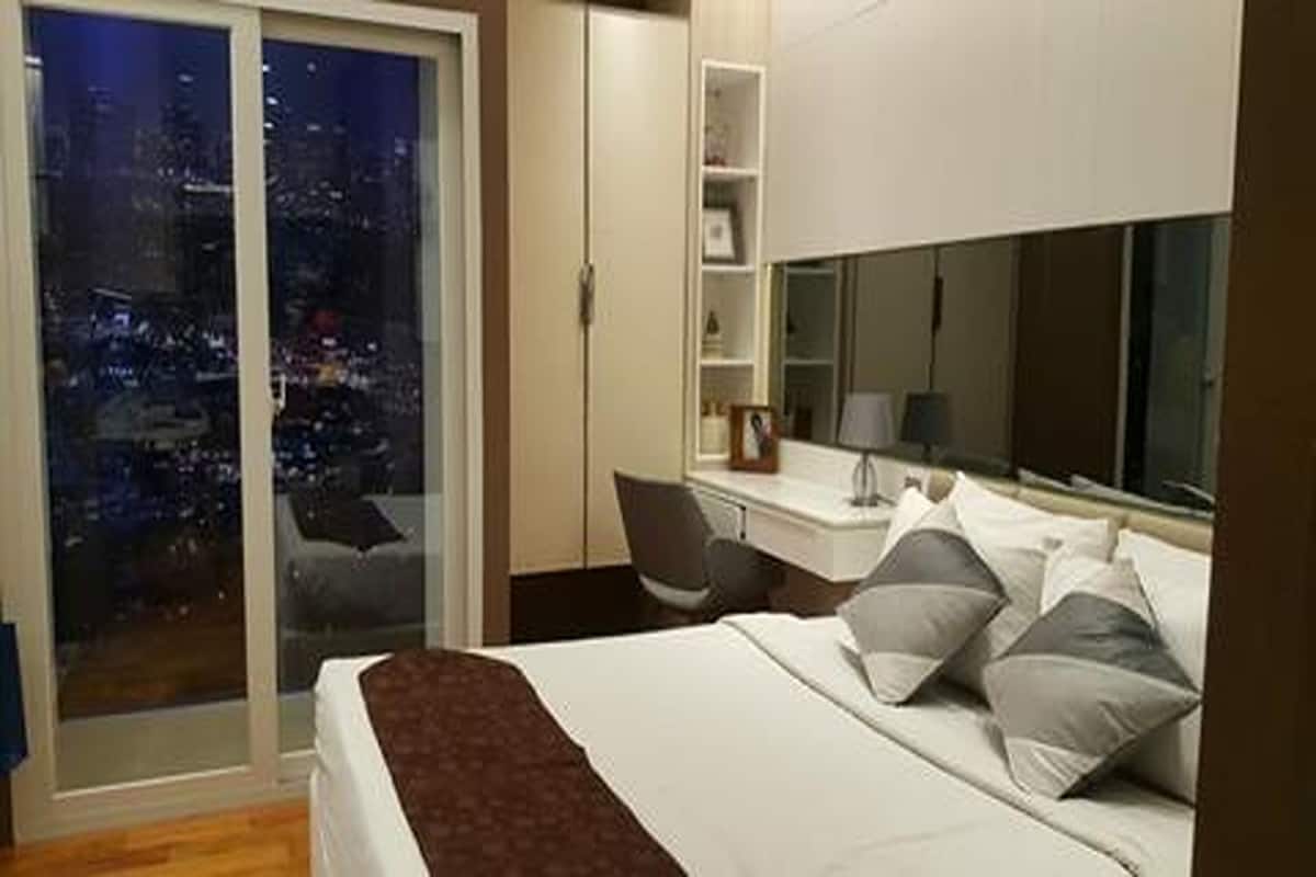 Ein Hotelzimmer mit einem Bett, einem Schreibtisch, einem Stuhl und einem großen Fenster mit Blick auf die Stadt.
