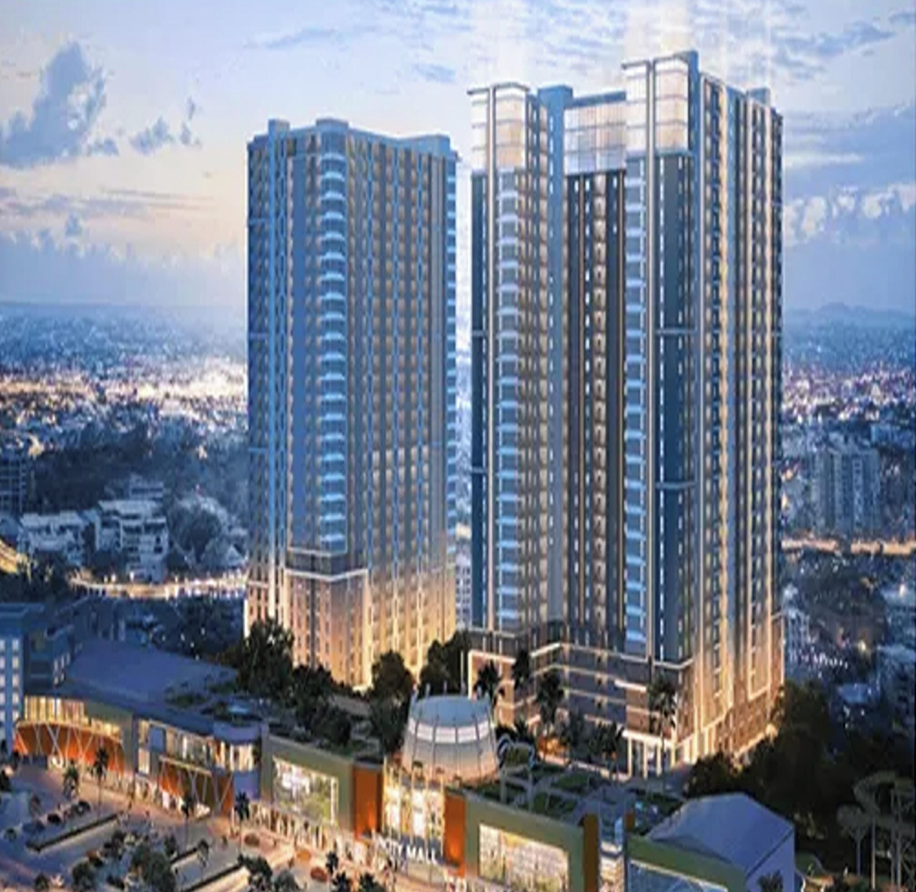 A high-rise residential building complex with multiple floors, surrounded by other buildings and a cityscape in the background.