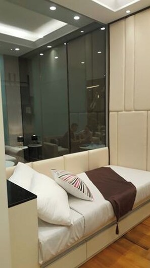 A modern bedroom with a sofa bed, a glass wall, and a view of a dining area. - SUN City Apartment Sidoarjo by Group A by Zuzu (Sidoarjo)