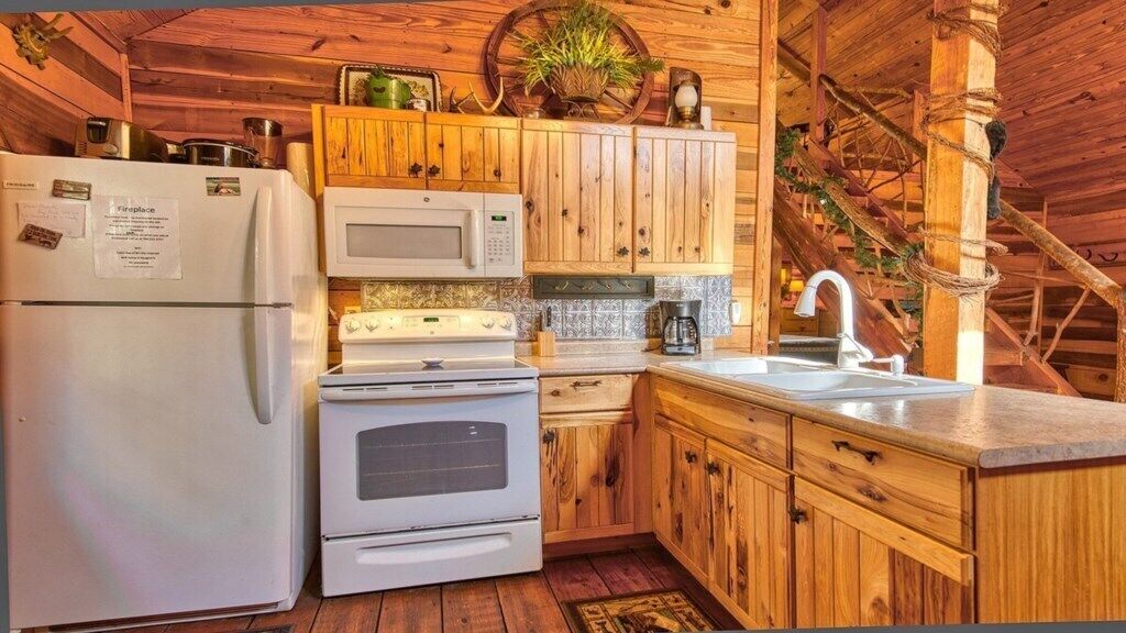 Una cocina rústica con gabinetes de madera, un refrigerador, un microondas, una estufa y un lavabo.
