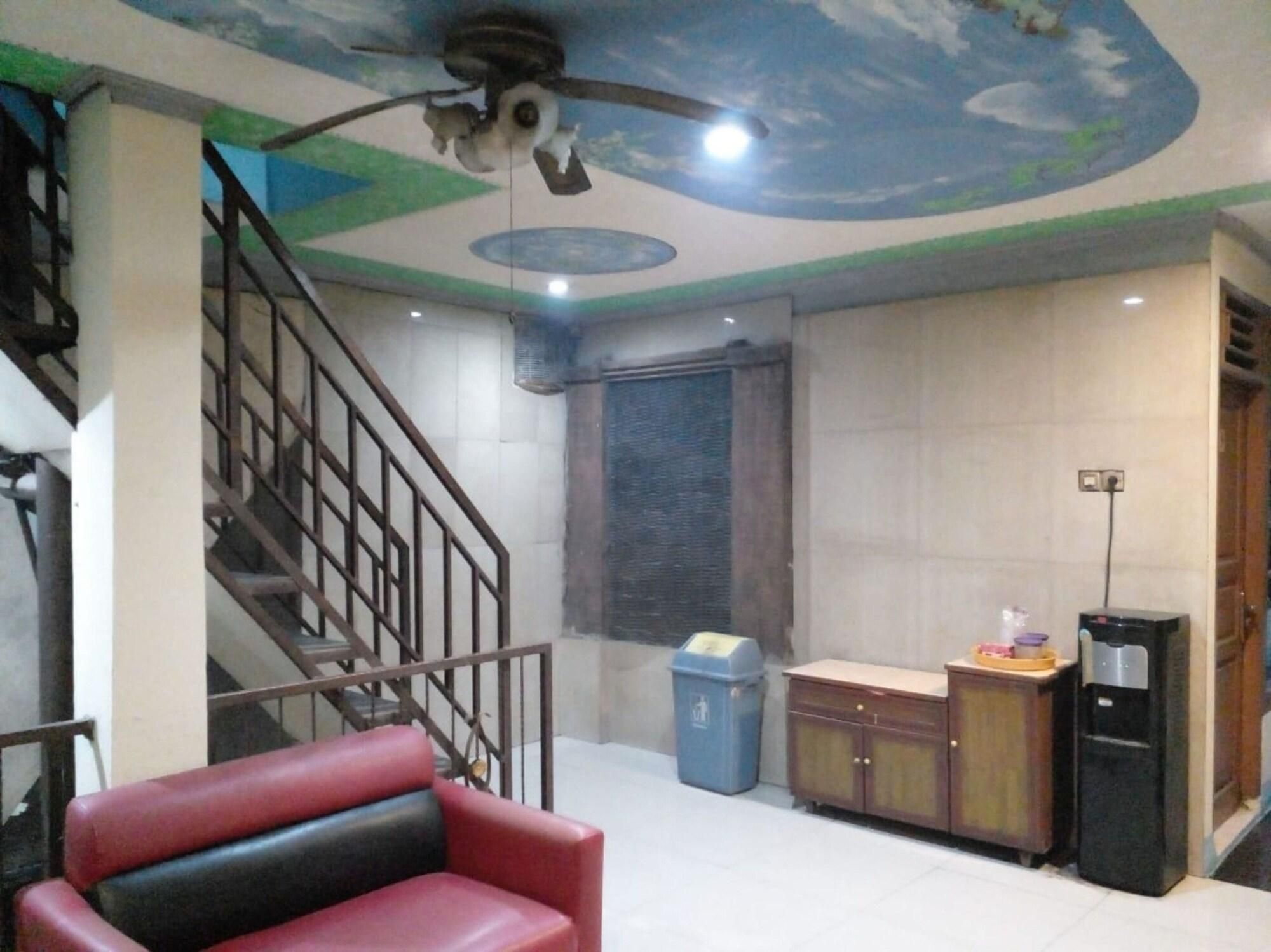 Une pièce avec un escalier, un ventilateur de plafond, une poubelle, un meuble et un distributeur d’eau.