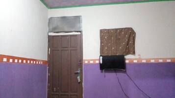 A room with a closed door, a wall-mounted air conditioner, and a patterned curtain.