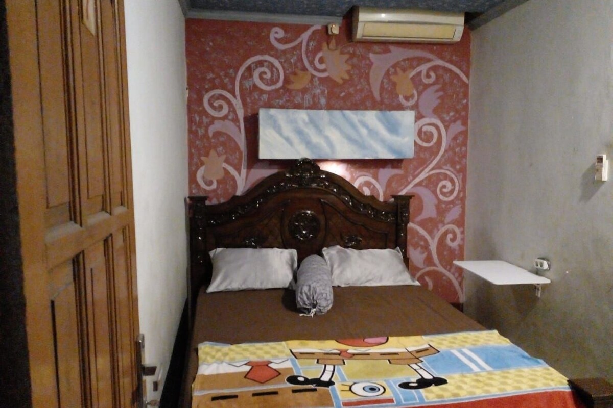 A bedroom with a wooden bed, a patterned wall, and a small bedside table.