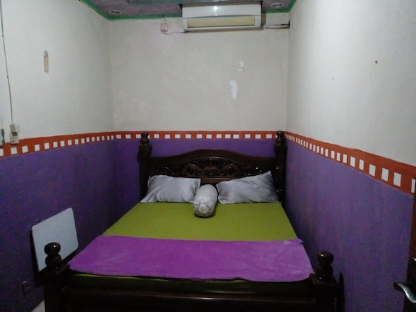 A small, single-bed room with a wooden headboard, a green and purple bedspread, and a white pillow. - Hotel Alifah 1 by Zuzu (Tangerang)